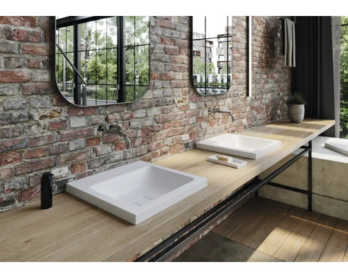 Badezimmer mit Waschbecken, Armaturen, Spiegeln und Holzarbeitsplatte vor Ziegelwand