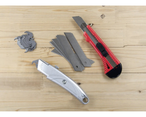 Zwei Cuttermesser und Klingen auf Holzgrund