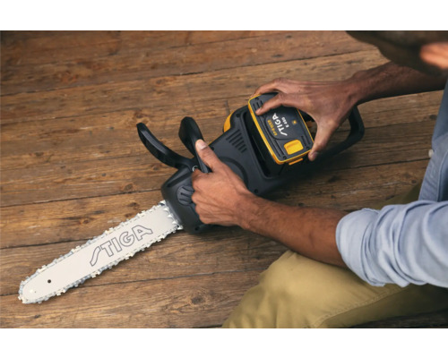 Eine Person setzt einen Akku in eine Akku-Kettensäge von Stiga ein.