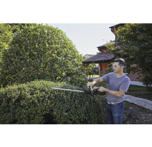 Mann schneidet Hecke mit einer Heckenschere