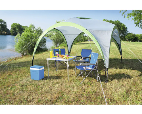 Campingplatzszene mit Pavillon, Tisch, Stühlen und Kühlbox auf einer Wiese am See