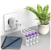 Ladegerät mit vier AA Batterien, Notizbuch und Stift auf einem Tisch