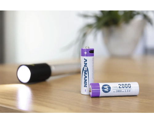 Zwei Ansmann AA Batterien und eine Taschenlampe auf einem Tisch