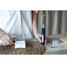 Milchaufschäumer mit Milchkanne und Batterien auf einem Tisch