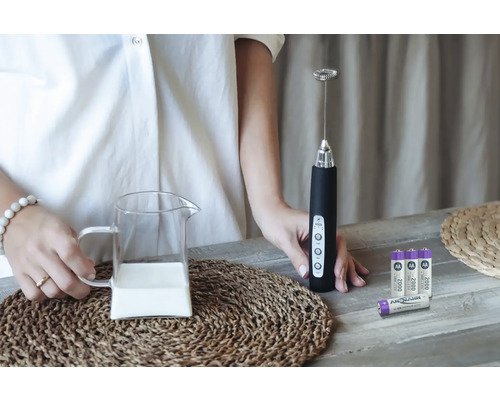 Milchaufschäumer mit Milchkanne und Batterien auf einem Tisch