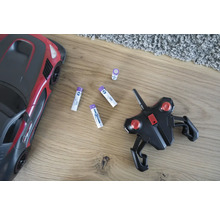 Spielzeugauto, Fernbedienung und Batterien auf einem Holzboden