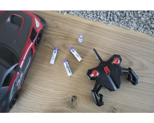 Spielzeugauto, Fernbedienung und Batterien auf einem Holzboden