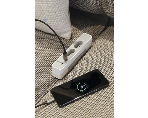 Mehrfachsteckdose und ein Smartphone werden mit einem Ladekabel verbunden.