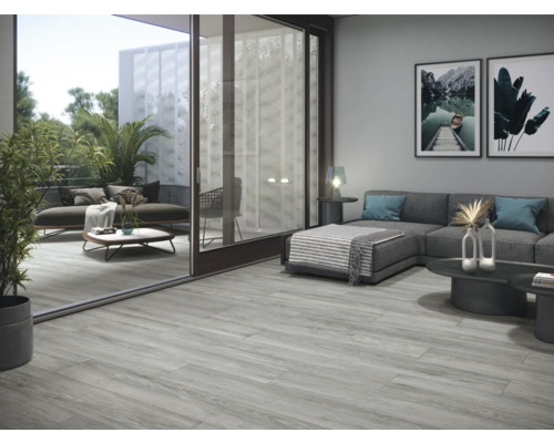 Wohnzimmer mit grauen Bodenfliesen in Holzoptik und Zugang zum Balkon