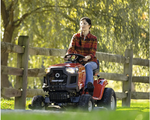 Frau fährt Rasentraktor der Marke Troy-Bilt im Garten