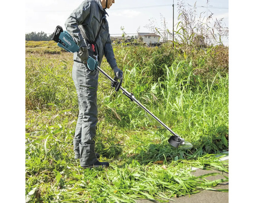 Eine Person bedient einen Akku-Rasentrimmer von Makita im Garten.