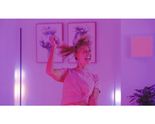 Frau tanzt in einem hell erleuchteten Raum mit Kunstwerken an der Wand