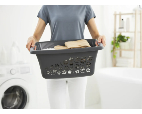 Frau hält einen Wäschekorb aus Kunststoff mit Wäsche