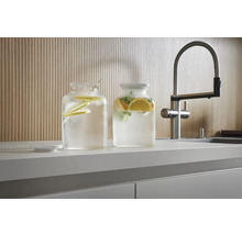 Zwei Glasbehälter mit Zitrusfrüchten und Wasser auf einer Küchentheke neben einem Wasserhahn