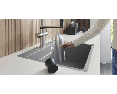Einbauküchenspüle mit Wasserhahn beim Befüllen einer Trinkflasche