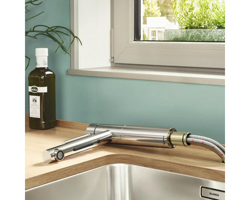 Küchenspüle mit ausziehbarer Armatur, Olivenölflasche und Fenster im Hintergrund.