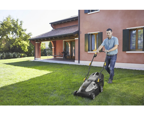 Mann benutzt einen Akku-Rasenmäher im Garten.