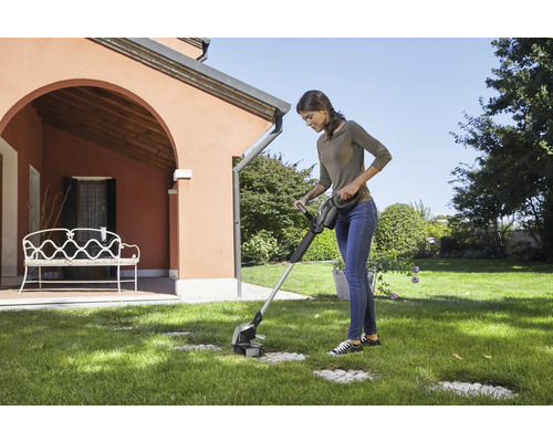 Frau benutzt Rasenkantenschneider im Garten