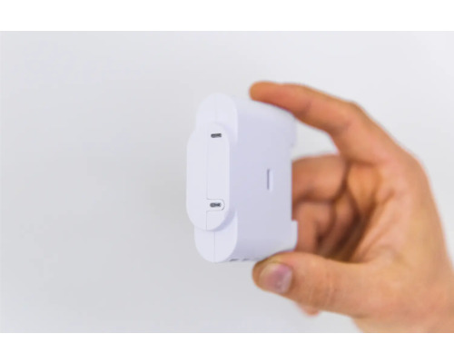 Hand hält einen weißen Shelly-Energiesensor