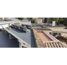 Installation von Solarmodulen auf einem Dach mit Ziegeln und Bitumenabdichtung.