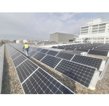 Aufnahme von Solarmodulen auf einem Dach mit einer Person, die eine Sicherheitsweste trägt