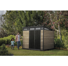 Gartenszene mit Gerätehaus, Mann und Kind auf Rasenfläche.