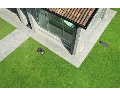 Rasenroboter auf Rasenfläche vor modernem Wohnhaus