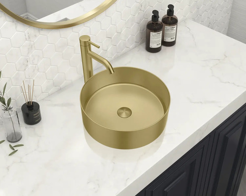 Auf einem Waschtisch befindet sich ein goldfarbenes Aufsatzwaschbecken mit Armatur