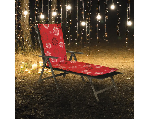 Gartensessel mit roter Auflage und Blumenmuster vor beleuchtetem Hintergrund