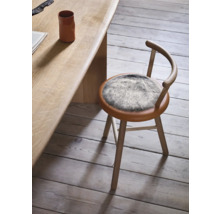 Holzstuhl mit Fellkissen am Tisch