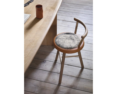 Holzstuhl mit Fellkissen am Tisch
