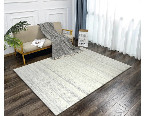 Wohnzimmer mit Sofa, Dekokissen und gemustertem Teppich auf Holzboden.