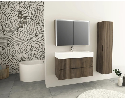 Modernes Badezimmer mit Waschtisch, Spiegelschrank und Hochschrank in Holzoptik vor einer Wand mit Pflanzenmuster.