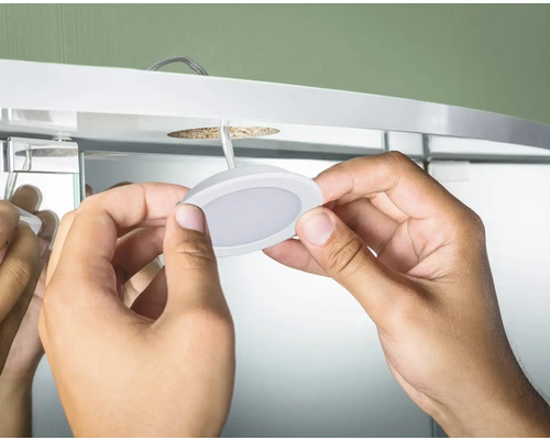 Installation einer runden LED-Unterbauleuchte in einem Spiegelschrank