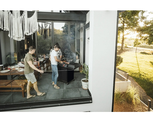 Personen grillen auf der Terrasse mit Grill und Gartenmöbeln