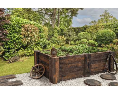 Holzhochbeet im Garten mit dekorativen Elementen wie Wagenrad und alter Laterne