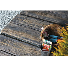 Gartenweg aus Betonplatten in Holzoptik mit Gartengeräten und Saatguttüten
