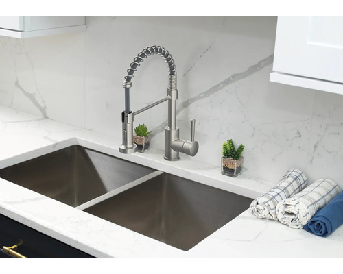 Küchenspüle aus Edelstahl mit Mischbatterie und Geschirrtüchern auf einer Arbeitsplatte aus Marmor.
