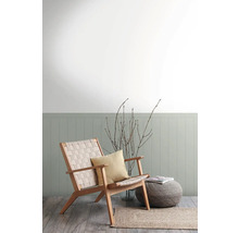 Wohnzimmer mit Sessel aus Holz, Kissen, Hocker und Teppich