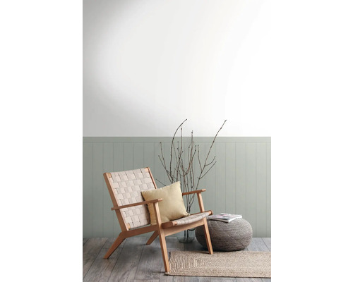 Wohnzimmer mit Sessel aus Holz, Kissen, Hocker und Teppich