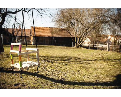 Holzschaukel mit farbigen Akzenten im Garten