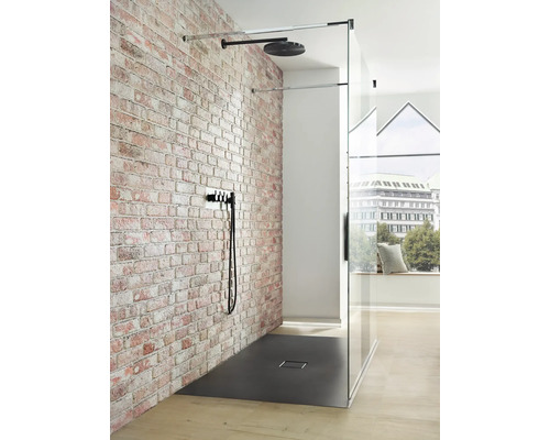 Begehbare Dusche mit verglaster Duschkabine, Kopfbrause und Armatur vor einer Ziegelwand