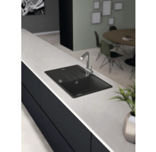 Schwarzes Spülbecken mit Wasserhahn auf einer Arbeitsplatte in der Küche.