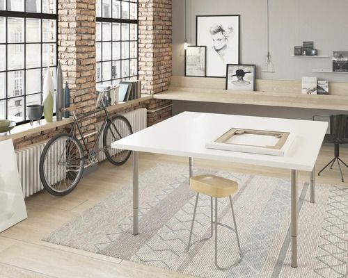 Heller Raum mit großem Fenster, Ziegelwand, weißem Tisch, Hocker und Fahrrad