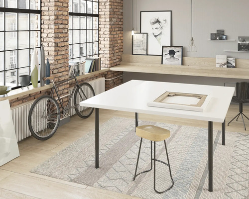 Werkraum mit weißem Tisch, Hocker und Fahrrad vor einem Fenster