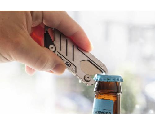 Eine Hand öffnet mit einem silberfarbenen Multifunktionswerkzeug eine Bierflasche.