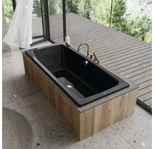 Schwarze Badewanne mit Holzverkleidung und Armaturen vor Fenster