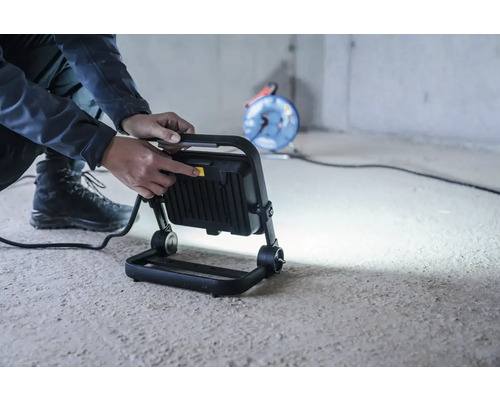 Arbeiter schaltet Baustrahler ein