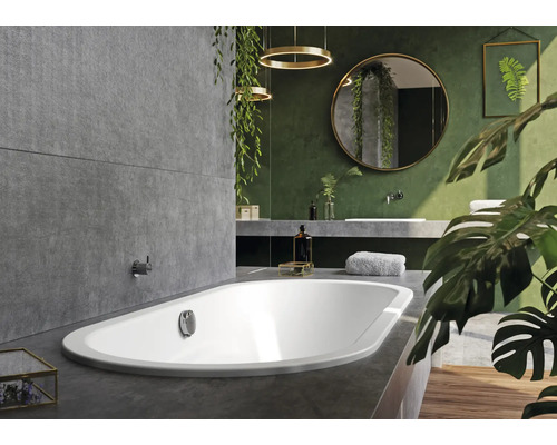 Badezimmer mit Badewanne, Waschbecken, Spiegel und Pflanzen für ein natürliches Ambiente