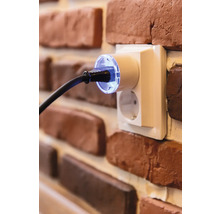 Steckdose mit eingestecktem Stecker an einer Backsteinmauer